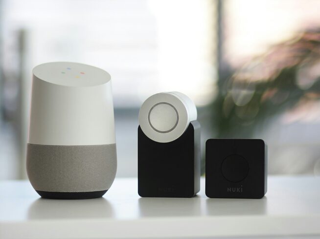 white and gray Google smart speaker and wo black speakers