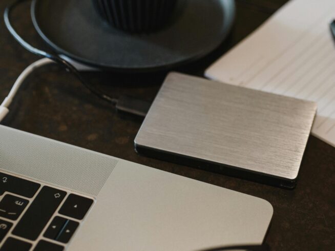 Free Closeup of an external hard drive connected to a laptop with a USB cable on a desk. Stock Photo