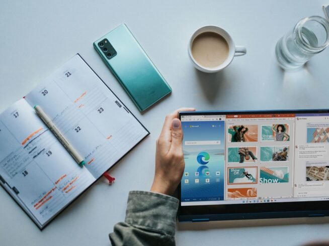 person using Windows 11 computer beside white ceramic mug on white table