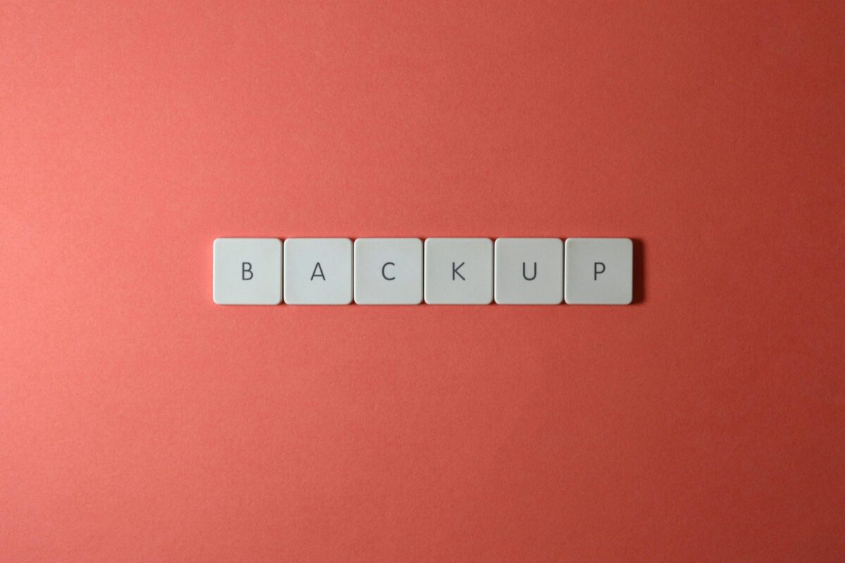 Free Close-up of keyboard keys spelling 'BACKUP' placed on a coral-colored surface. Stock Photo