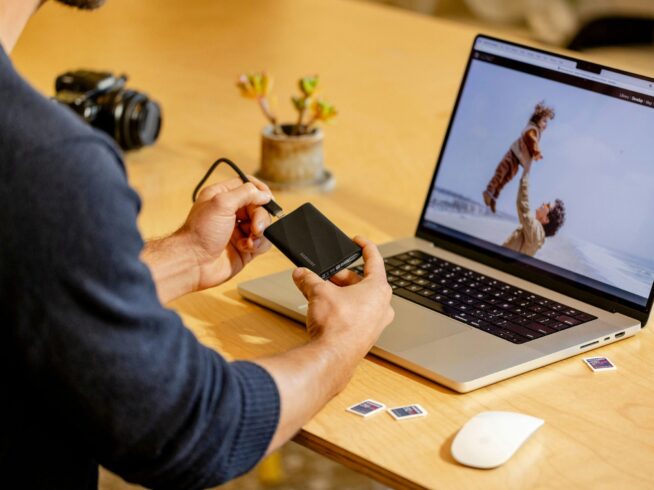 A man sitting at a table with a laptop and cell phone