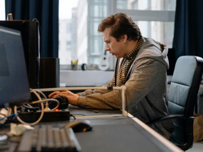 Free A concentrated professional working at a computer in a modern office setting. Stock Photo