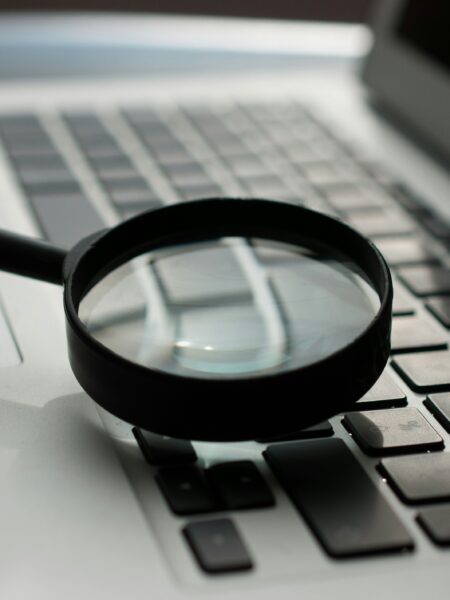 magnifying glass near gray laptop computer